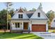 Charming two-story home with a covered porch, wood garage door, and manicured lawn at 12845 Mallard Rock Rd, Zebulon, NC 27597