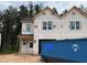 New two-story home under construction featuring newly-installed windows, black roof, and adjacent construction dumpster at 15 Calluna Dr, Clayton, NC 27520
