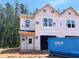Exterior view of a new construction home featuring a blue dumpster ready for construction debris at 15 Calluna Dr, Clayton, NC 27520
