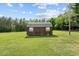 Exterior view of an outbuilding with a metal roof on a green lot with trees in the background at 1510 Asbury Church Rd, Sanford, NC 27330