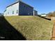 The backyard features a newly built home with blue siding on a grassy hill under a bright blue sky at 1667 Pecan Drive # 25, Nashville, NC 27856