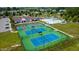 Aerial view of community featuring tennis courts and a clubhouse with parking, surrounded by lush greenery at 1910 Morehead Hill Ct, Durham, NC 27703