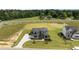 Stunning aerial view of a two-story home with a stone facade, a long driveway, and green lawns at 200 Broadleaf Ln, Youngsville, NC 27596