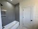 Bathroom featuring a tiled shower, white tub, grey walls, and modern fixtures at 200 Broadleaf Ln, Youngsville, NC 27596