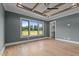 This bedroom features tray ceilings, hardwood floors, large windows, and a closet at 200 Broadleaf Ln, Youngsville, NC 27596