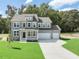 Two-story home with gray siding, white trim, large windows, covered porch, and three-car garage at 203 Great Smoky Pl, Lillington, NC 27546