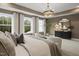 Spacious main bedroom featuring large windows, seating area, and stylish chandelier at 203 Great Smoky Pl, Lillington, NC 27546