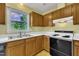 Close-up of the kitchen featuring wood cabinets, stainless steel sink, and a white electric stove at 205 Lizzie King Ct, Willow Springs, NC 27592