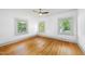 Sun-filled empty bedroom with hardwood floors and three windows offering lush green views at 223 Hawthorne Rd, Raleigh, NC 27605