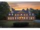 Stately brick home featuring symmetrical design, dormer windows, shutters, and professional landscaping at sunset at 2238 Lakeview Ter, Burlington, NC 27215