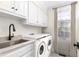 Bright laundry room with white cabinets, modern washer and dryer, sink and granite countertops at 2238 Lakeview Ter, Burlington, NC 27215