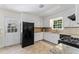 A well-lit kitchen with black appliances, white cabinets, neutral backsplash and tiled floors at 306 Holland Rd, Fuquay Varina, NC 27526