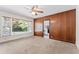 Sunlit living room featuring wood paneling, large windows, and an open doorway to the kitchen at 306 Holland Rd, Fuquay Varina, NC 27526