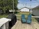 View of backyard wooden deck featuring multiple grills, blue seating, and a lush green lawn at 309 Westfield Dr, Dunn, NC 28334