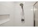 Close-up of a shower featuring a modern showerhead, sleek white tile, and a built-in niche for toiletries at 310 Pilot Ridge Rd, Zebulon, NC 27597