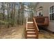 A view of the deck's stairs leading down to the backyard, surrounded by towering trees at 338 Howland Ct, Creedmoor, NC 27522