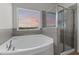 Bright bathroom with a large bathtub, separate shower, and scenic sunset view from the window at 520 Austin View Blvd, Wake Forest, NC 27587