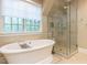 Well-lit bathroom with a tub, glass enclosed shower, and large window at 5420 Deer Forest Trl, Raleigh, NC 27614