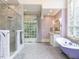 Bright bathroom featuring a clawfoot tub, glass shower, and a large window view at 5420 Deer Forest Trl, Raleigh, NC 27614