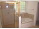 Bathroom features a separate shower and bathtub with tile accents and a window at 6673 Nc 96 W Hwy, Youngsville, NC 27596