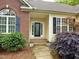 Close-up of front entrance with a decorative glass door, brick accents, and lush landscaping at 6673 Nc 96 W Hwy, Youngsville, NC 27596