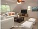 Staged living room with sofa, ottomans, TV, and area rug at 6673 Nc 96 W Hwy, Youngsville, NC 27596