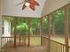 Charming screened-in porch with wood flooring and ceiling fan, surrounded by lush greenery for peaceful relaxation at 6673 Nc 96 W Hwy, Youngsville, NC 27596