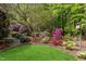 Lush backyard featuring azaleas, trees, and a bird house at 754 Olde Thompson Creek Ct Rd, Apex, NC 27523