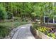 Lush backyard with a stone pathway, raised garden beds, trees and mature plantings at 754 Olde Thompson Creek Ct Rd, Apex, NC 27523