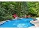 Sparkling blue pool with a stone waterfall feature and lush landscaping creating a private backyard oasis at 754 Olde Thompson Creek Ct Rd, Apex, NC 27523
