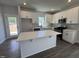 Modern kitchen features white cabinets, stainless steel appliances, a gray backsplash, and an island with a quartz countertop at 773 Portland Rose Dr, Knightdale, NC 27545