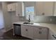 Bright kitchen sink area showcasing stainless steel appliances, white cabinets, grey backsplash, and dark hardware at 773 Portland Rose Dr, Knightdale, NC 27545