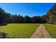 Expansive green front yard with lush grass and a winding gravel path leading into the wooded area at 79 Mildred Dr, Broadway, NC 27505