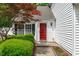 Charming front entrance featuring a vibrant red door, lush landscaping, and a welcoming pathway at 104 Harvolly Dr, Holly Springs, NC 27540