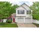 Charming two-story home featuring a bright red door, a two car garage and complemented by mature trees and landscaping at 104 Harvolly Dr, Holly Springs, NC 27540