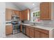 A kitchen featuring modern stainless steel appliances, warm wood cabinetry, and light countertops for an inviting cooking space at 104 Harvolly Dr, Holly Springs, NC 27540