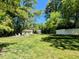 Lush backyard featuring a large lawn, mature trees, and an outdoor seating area with a fire pit at 107 Forest Rd, Oxford, NC 27565