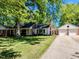 Exterior view of home with brick accents and a detached two-car garage, surrounded by mature trees and green lawn at 107 Forest Rd, Oxford, NC 27565