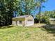 Detached one-car garage with a yellow exterior, surrounded by a green lawn and mature trees at 107 Forest Rd, Oxford, NC 27565