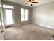 A bright bedroom with neutral carpet, ceiling fan, and a door to the outside at 113 Conner Dr # 103, Chapel Hill, NC 27514