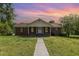Charming brick home with a manicured lawn and inviting front porch under a beautiful sunset sky at 1303 Cherry Dr, Burlington, NC 27215