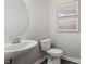 Powder room with pedestal sink, framed art, modern round mirror, and wood look flooring at 137 Cultivator Ct, Angier, NC 27501