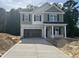 Two-story home featuring an open garage, green siding, a covered porch, and a new concrete driveway at 183 Pecan Valley Way, Four Oaks, NC 27524