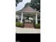 An inviting white gazebo features a picnic table, ceiling fan and is surrounded by green landscaping at 183 Pecan Valley Way, Four Oaks, NC 27524