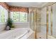 Bright bathroom featuring bathtub, glass enclosed shower, and floral-patterned valance above window at 205 Buncombe St, Raleigh, NC 27609