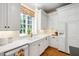 Bright kitchen featuring custom white cabinets, a farmhouse sink and a large window overlooking a green yard at 205 Buncombe St, Raleigh, NC 27609