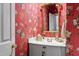 Stylish powder room with red floral wallpaper, gold mirror and white vanity at 205 Buncombe St, Raleigh, NC 27609