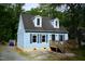 Charming Cape Cod home with light blue siding, a wood deck, and dormer windows nestled in a lush, green setting at 2315 George Anderson Dr, Hillsborough, NC 27278