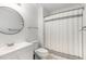 Clean bathroom featuring single vanity, round mirror, and shower-tub combo at 2540 Beech Gap Ct, Raleigh, NC 27603