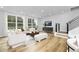 Bright living room with light wood floors, white sofas, chairs, curtains, area rug, and modern staircase at 3018 White Rail Dr, Fuquay Varina, NC 27526